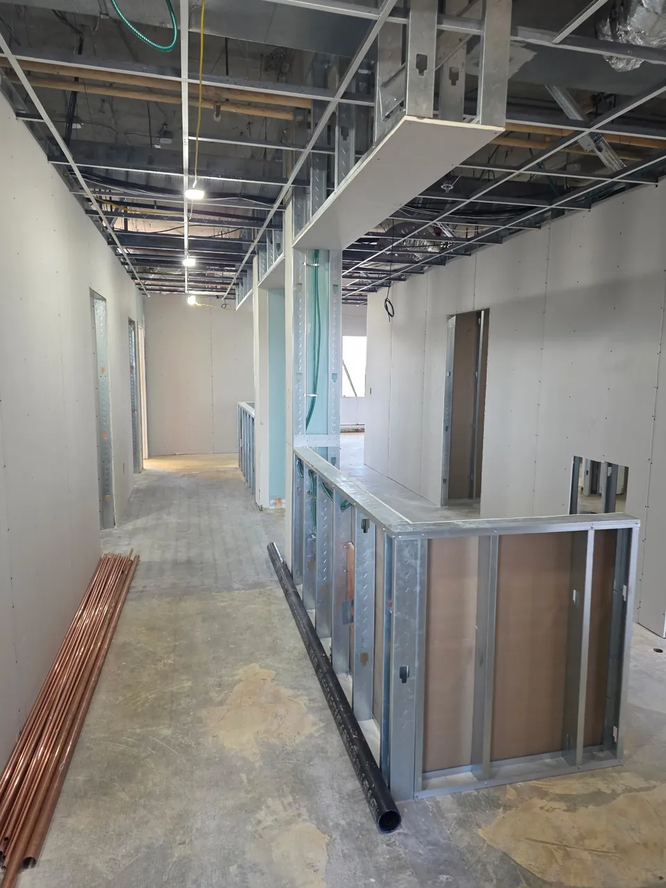 Clinical corridor during rough-in with framed nurse station and copper plumbing supply on site