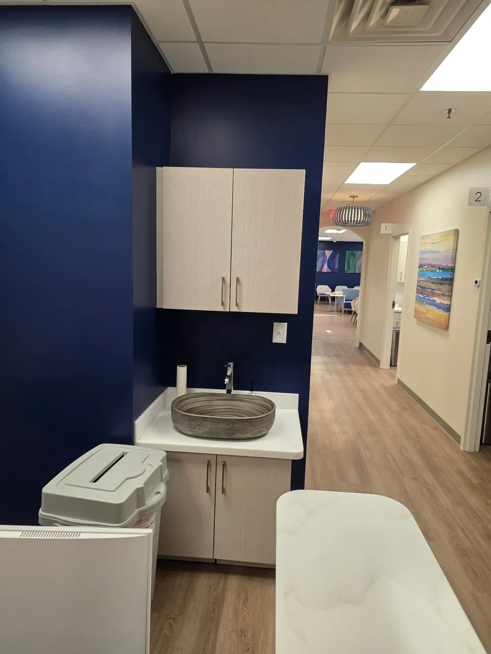 Staff hand-wash station with casework and vessel sink in a medical office corridor