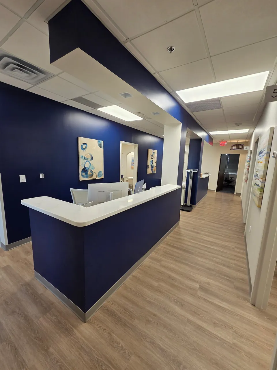 Completed nurse station with quartz countertop and navy bulkhead in a medical office corridor