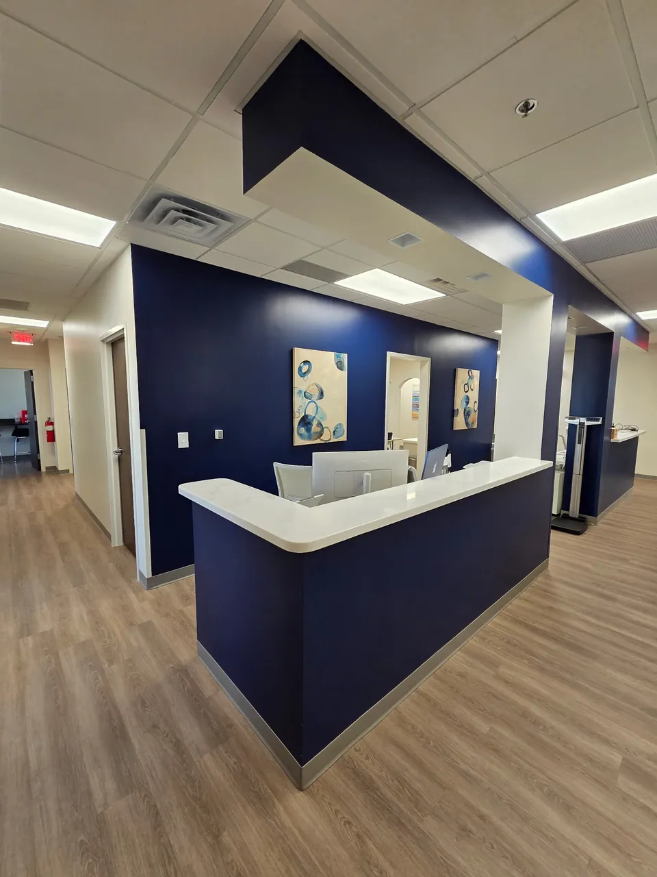 Medical office clinical corridor with nurse station, exam room doors and wood-look vinyl plank flooring