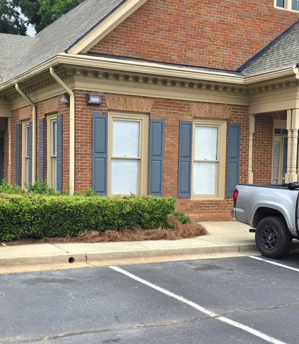 Completed brick office building exterior after wall reconstruction, with matched brick veneer, new window and shutters
